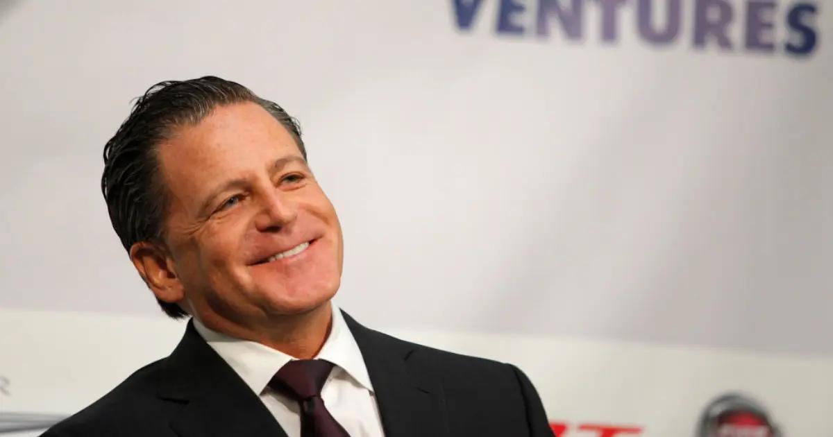 A happy Dan Gilbert wearing a suit and tie.