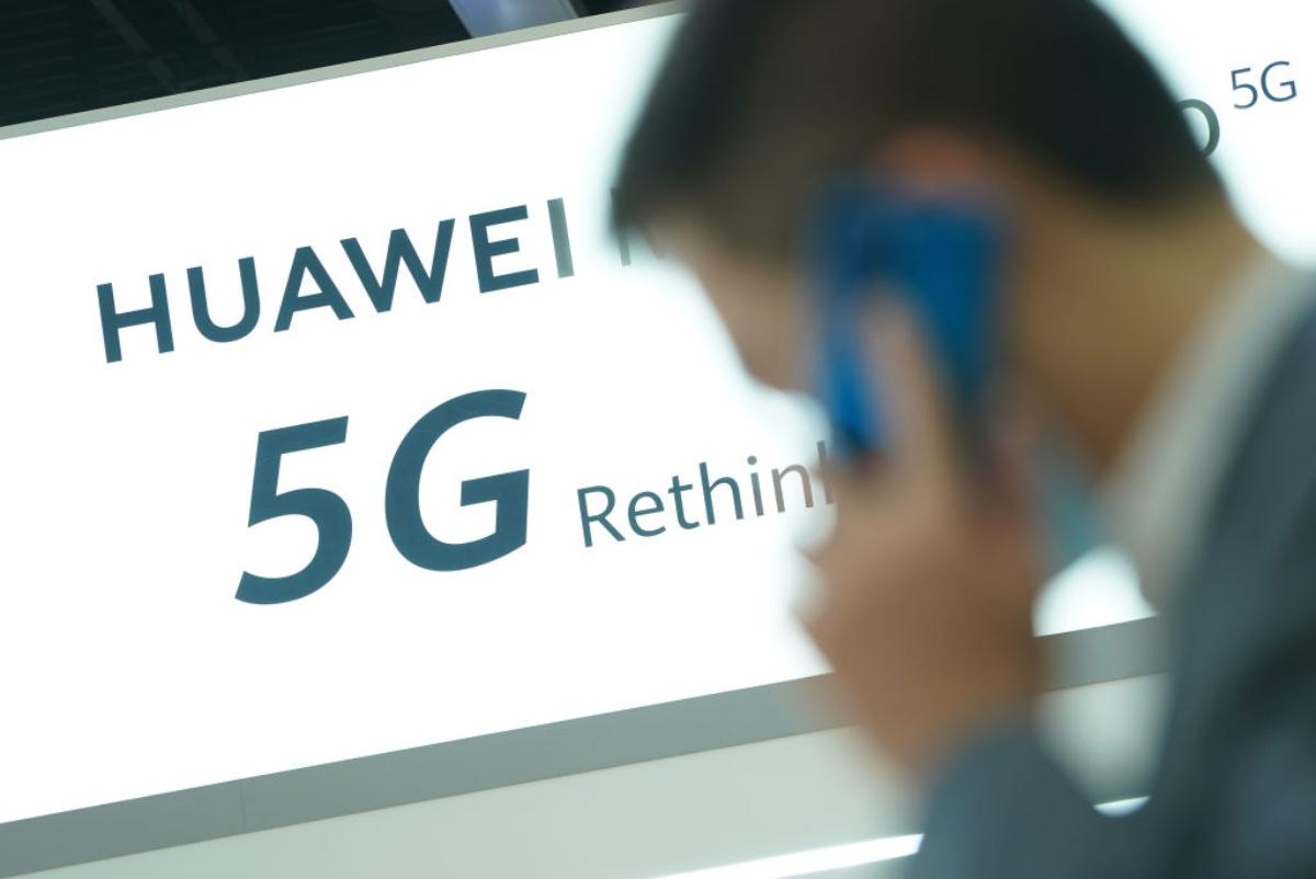 Huawei 5G advertisement with a man on a cellphone walking in front of it