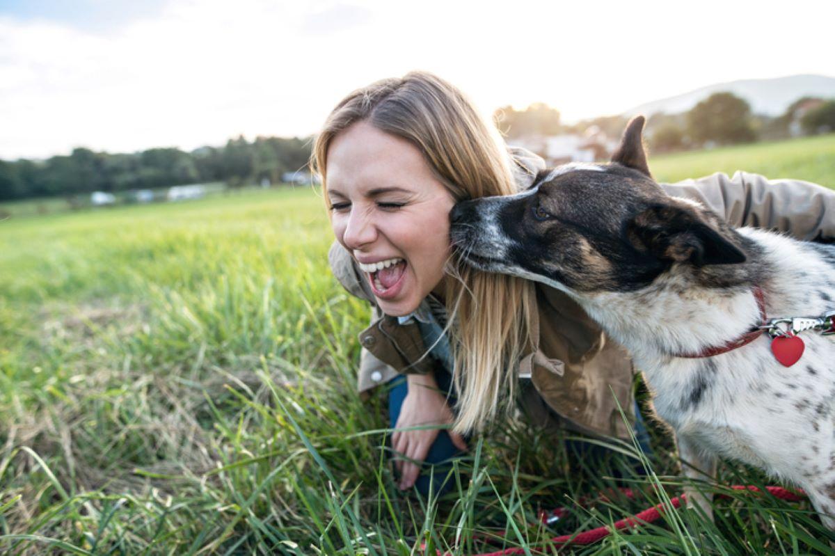 A young woman with a dog licking her cheek