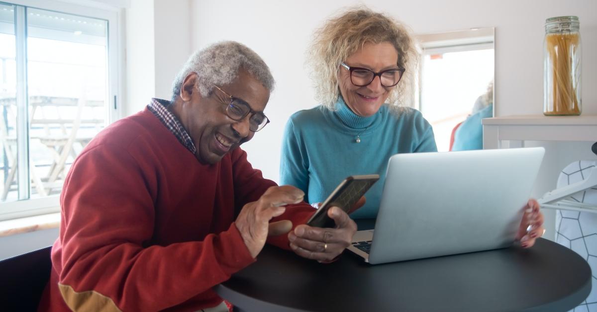 Two seniors looking at their phone and laptop