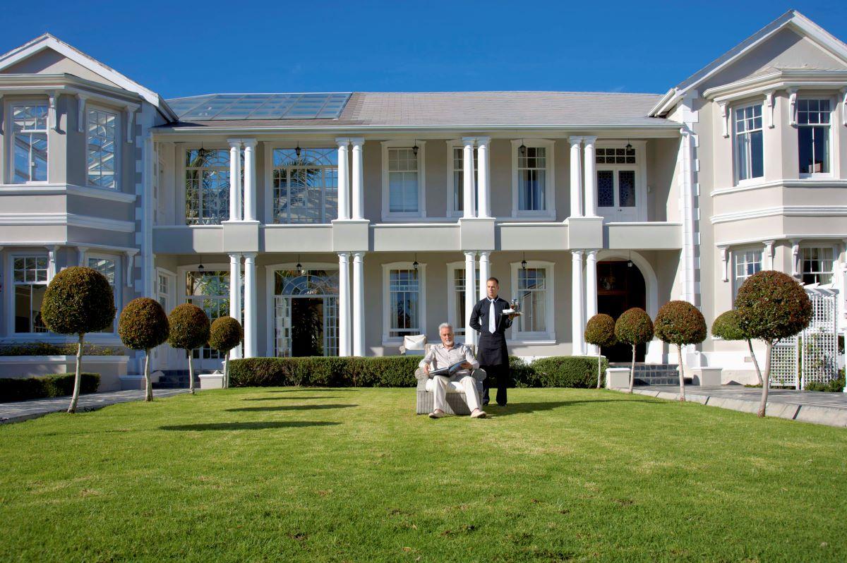 A rich man sitting on his lawn with his butler