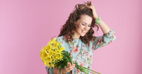 A woman wearing spring clothes and holding flowers