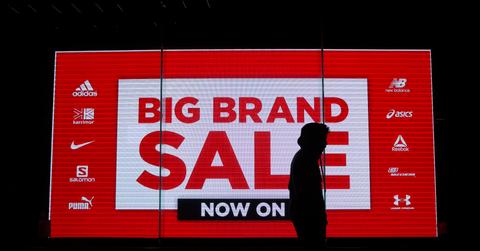 A person seen in front of a big brand sale sign advertising high-profile brand names