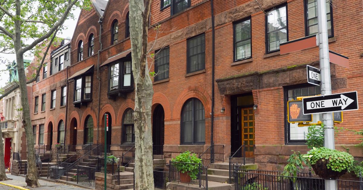 NYC brownstone apartments on a tree-lined street.