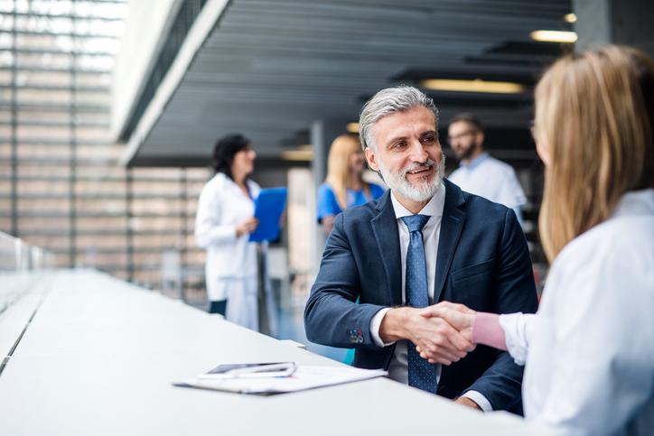 Doctors talking to man, shaking hands. 