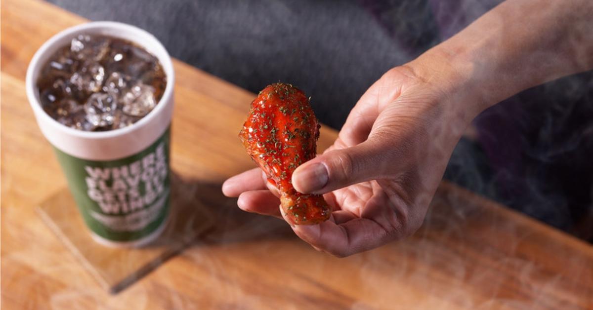 A man holding a Wingstop Blazed & Glazed wing.