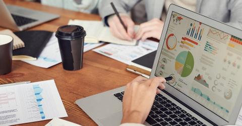 A person pointing to chart on a laptop