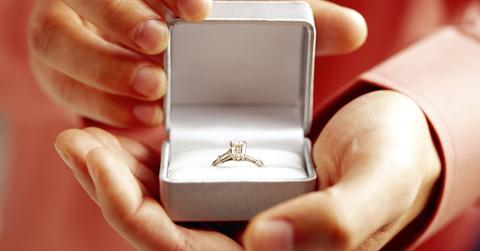 A person holding a diamond ring in a box