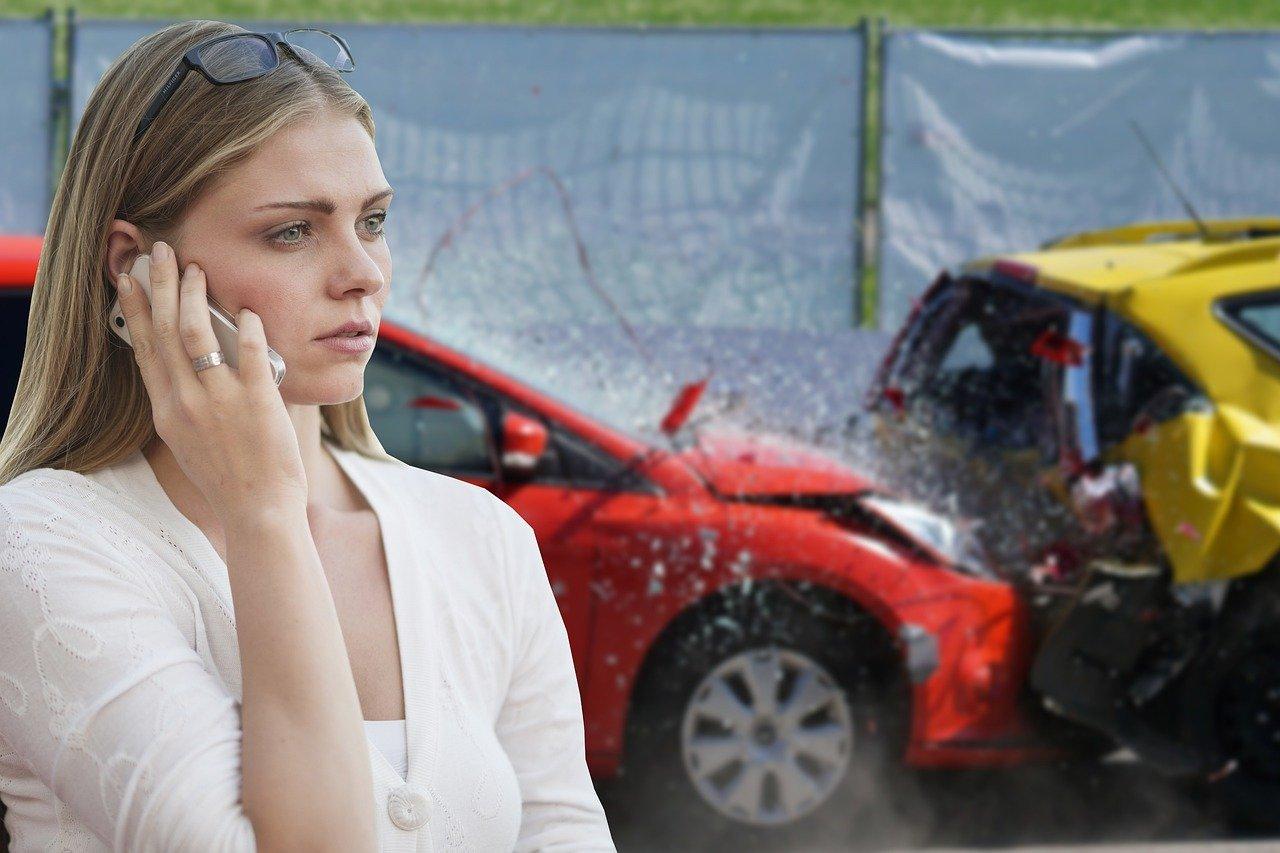 A woman on a call with a car crash in the background