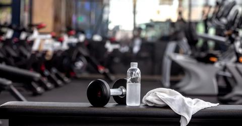 A weight, water bottle, and towel sit on gym equipment.