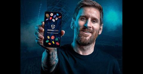 Lionel Messi holding a smartphone with the Socios.com app on it