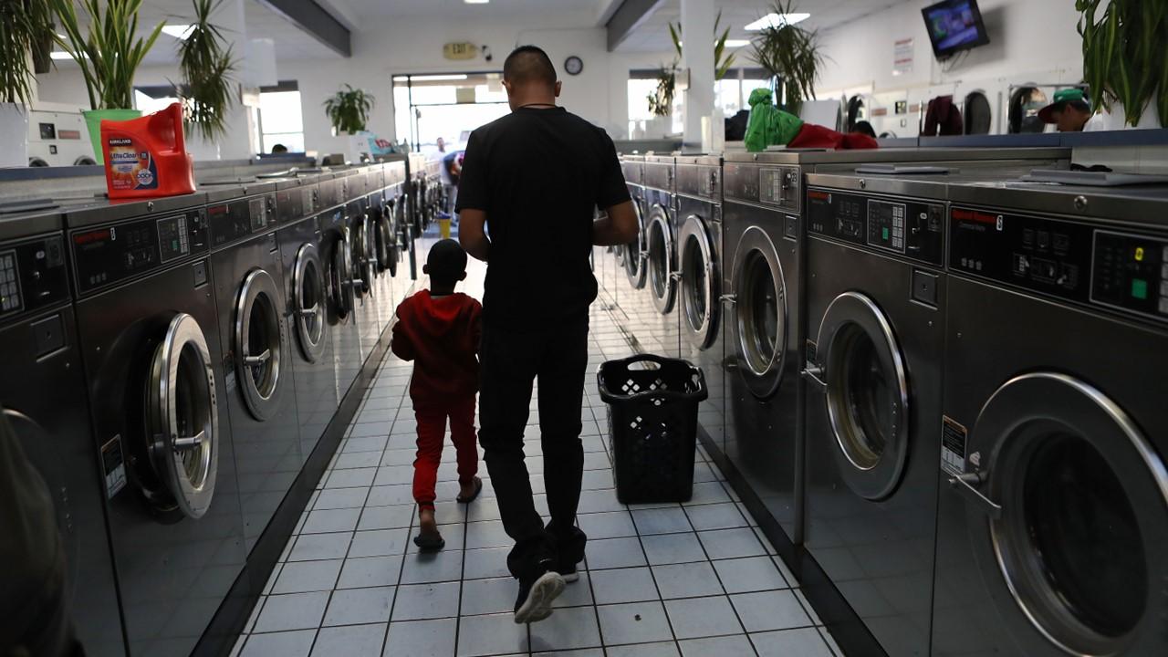 A man and boy walking in a laundromat