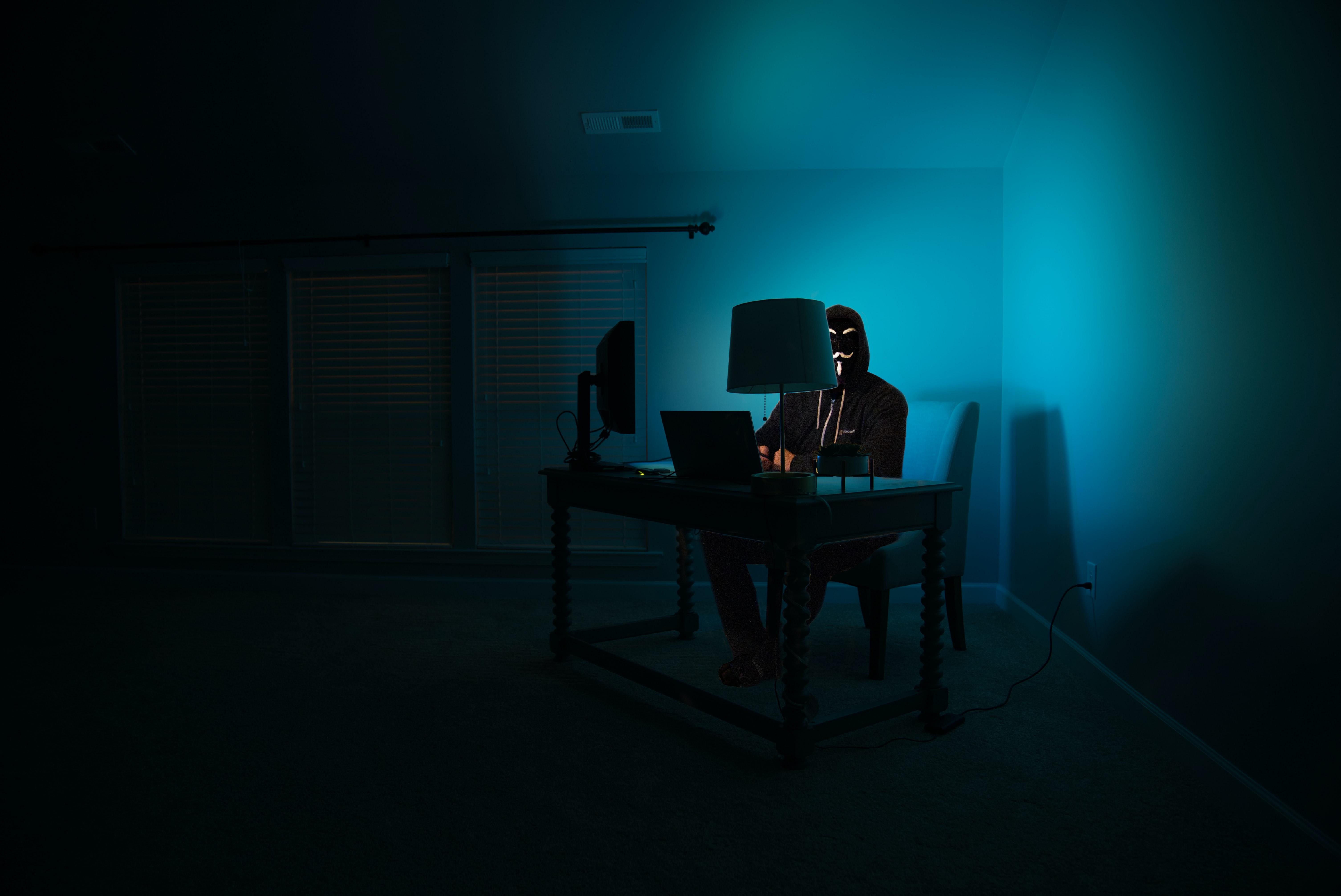Hacker in dark room at computer desk
