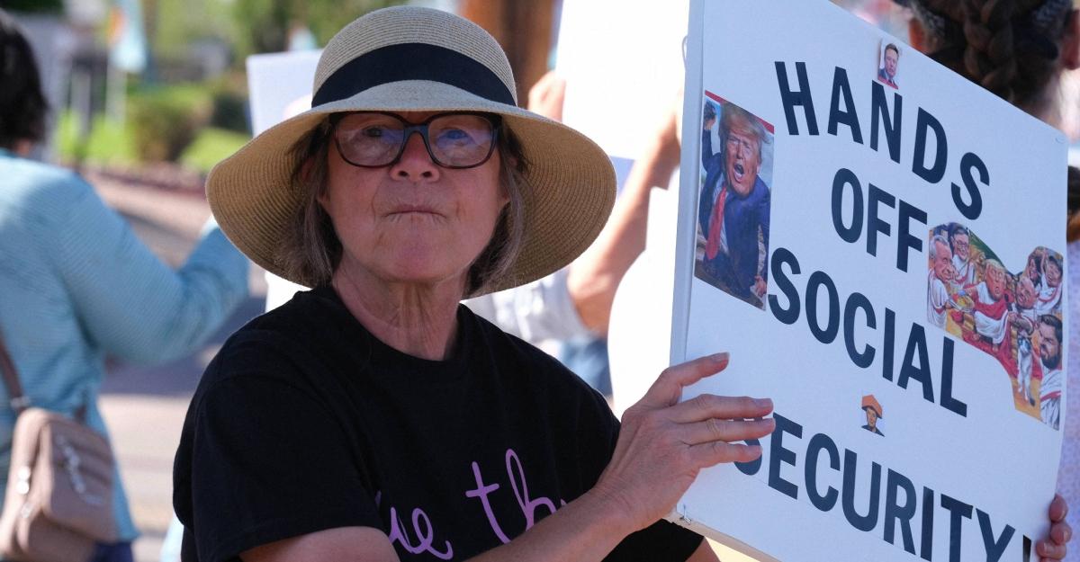 A woman holds a sign protesting Trump and cuts to Social Security benefits.