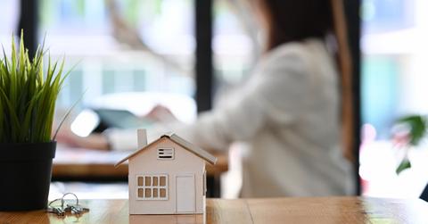 Small house model, keys, and a houseplant on wooden table