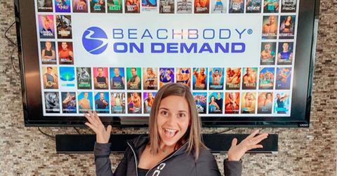 Woman in front of a tv with Beachbody on Demand on the screen
