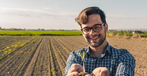 A farmer standing in a field with dirt in his hands