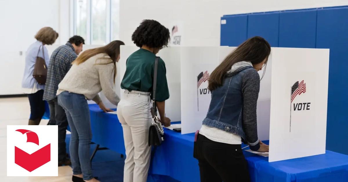 People line up at table to cast their vote privately.