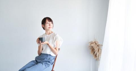 A woman sitting at the window enjoying a cup of coffee