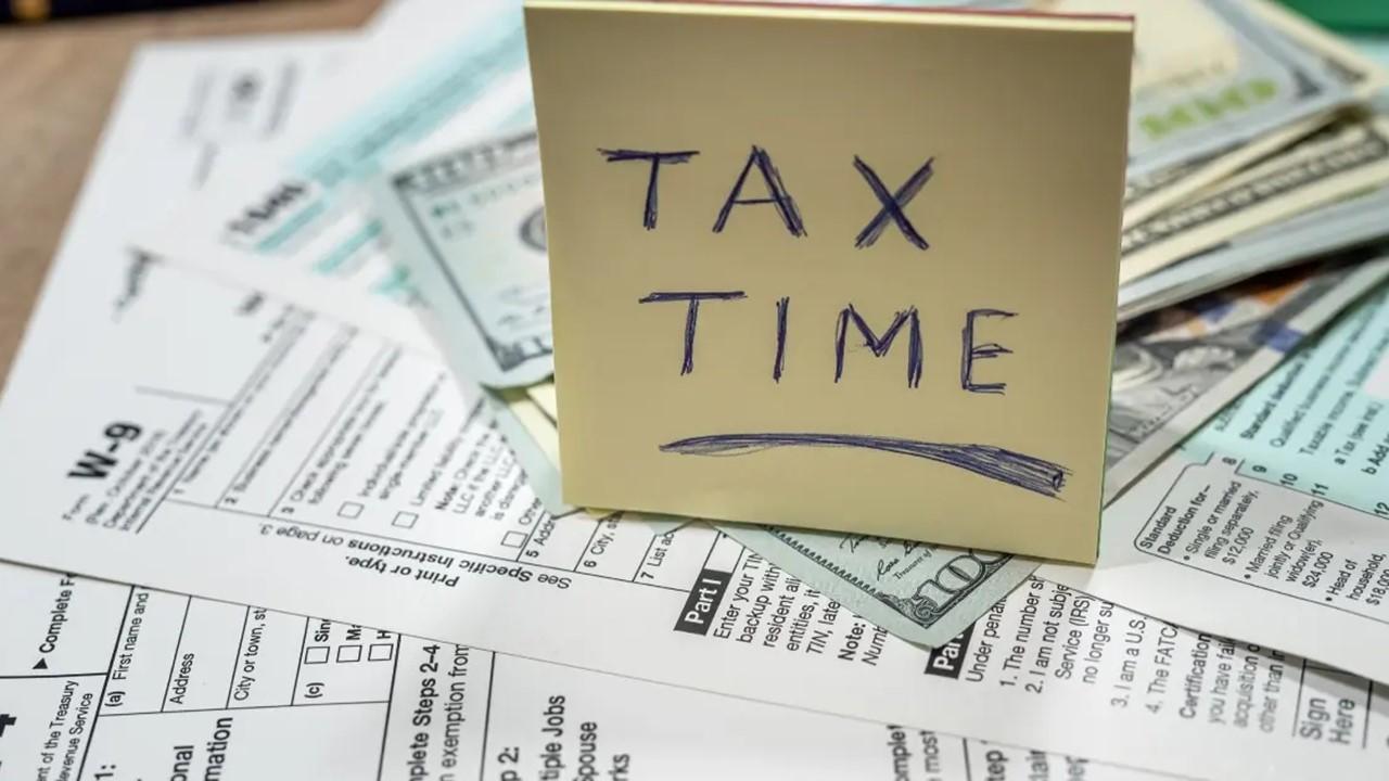 A tax time note, paperwork, and money on a table