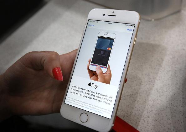 Woman's hand holding phone with Apple Pay