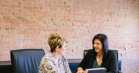 Two people sitting at a desk discussing data on a tablet