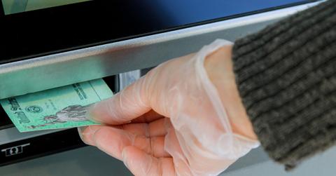 Closeup of hand entering deposit stimulus check into ATM machine