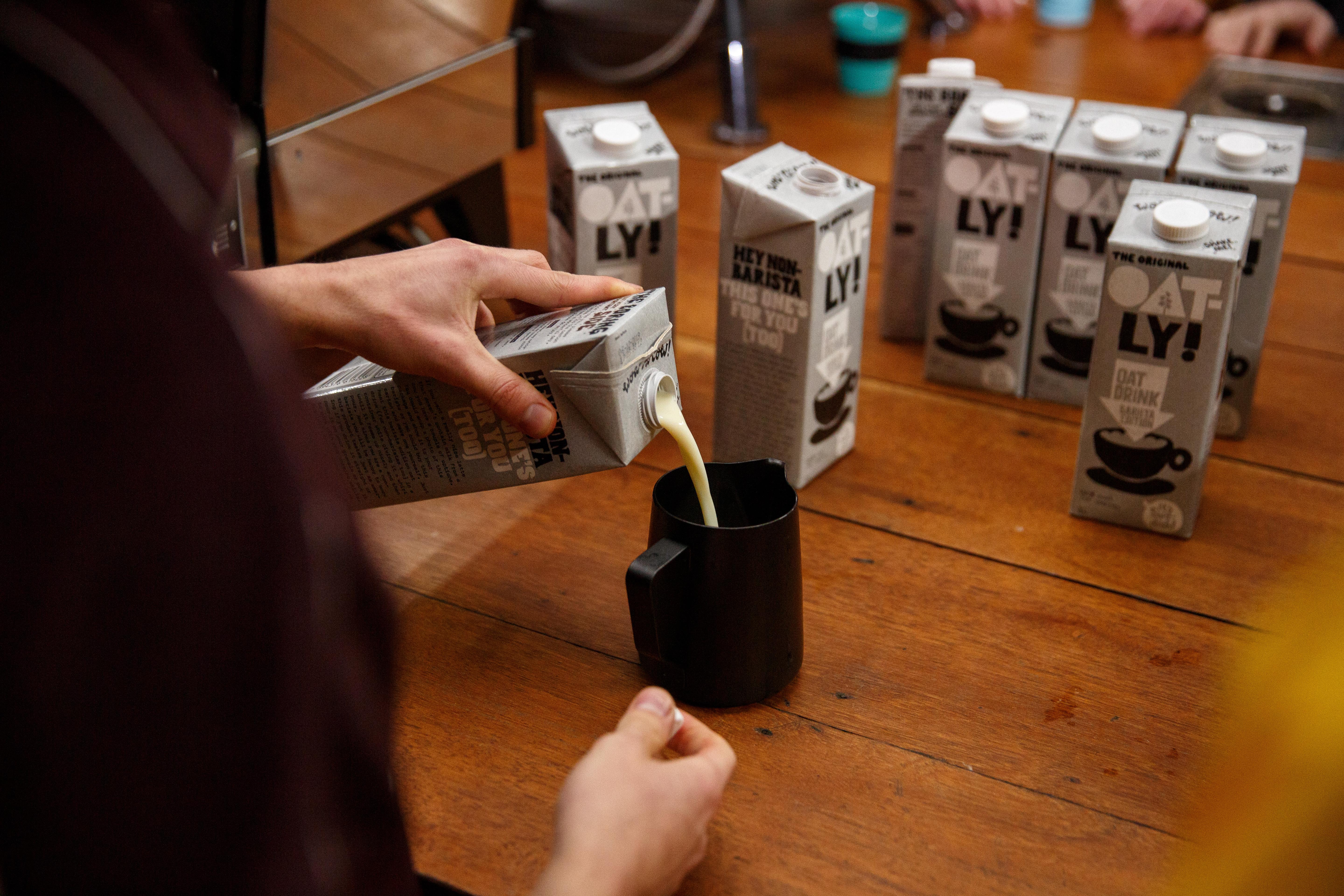 Person pouring Oatly milk into a cup